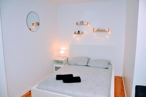 a small white bedroom with a bed and a mirror at Dormir près de Brioude - studio 'esprit vacances' in Fontannes