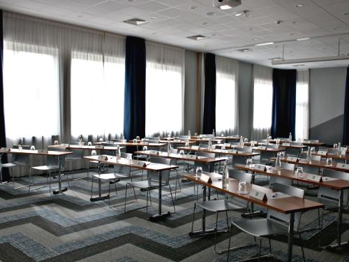 a classroom with tables and chairs in a room with windows at ibis Styles Avignon Sud in Avignon