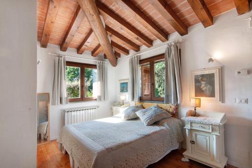 a bedroom with a bed and two windows at Villa Il Rossignolo con Piscina in Grassina