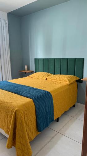 a bedroom with a large bed with a yellow blanket at Apartamento Studio 003 in Caruaru