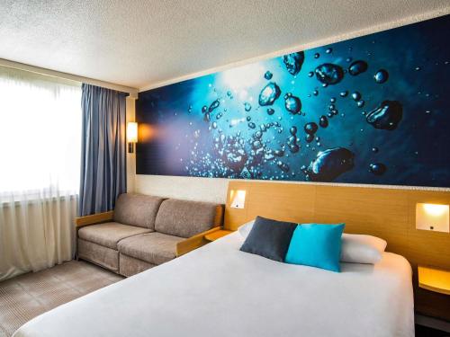 ein Hotelzimmer mit einem Bett und einer Couch in der Unterkunft Novotel Le Mans in Le Mans