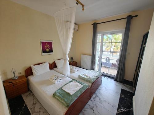 a bedroom with a bed with white sheets and a window at Villa Askamnia and Suites in Nikiti
