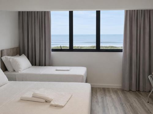a hotel room with two beds and a view of the ocean at Navega Beach Palace Hotel in Navegantes