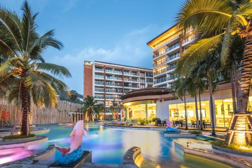 a resort pool with palm trees and a hotel at The Beach Heights Resort SHA Plus in Kata Beach