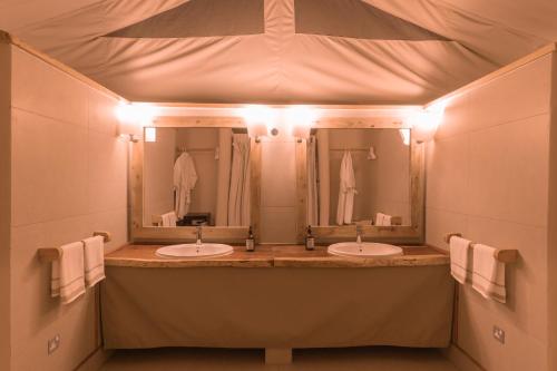 a bathroom with two sinks and a large mirror at Mara Maisha Camp in Talek