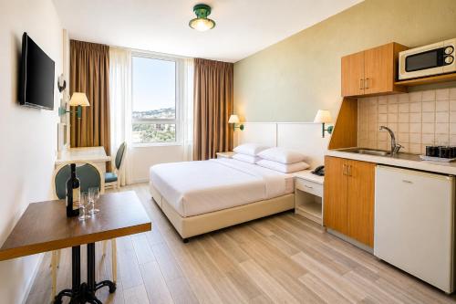 a hotel room with a bed and a kitchen at Marom Residence Romema in Haifa
