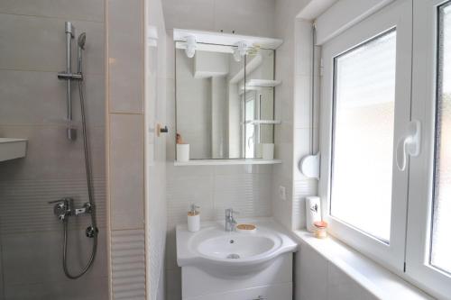 a white bathroom with a sink and a mirror at Bonaca Room in Donja Lastva