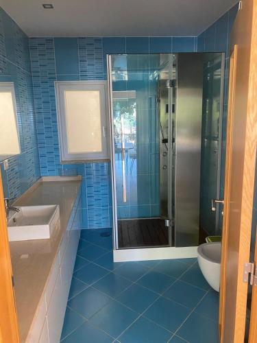a blue bathroom with a shower and a sink at Vale Do Gavim, Moitas in Trancoso