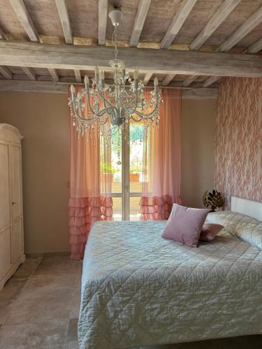 a bedroom with a bed and a chandelier at L’ Aia del Principe in Montepulciano