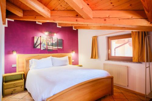 a bedroom with a large bed with purple walls at Residenza Garibaldi - Cirmolo in Molveno