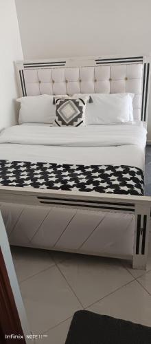 a white bed with a black and white comforter at Studio BNB Meru town CBD in Meru
