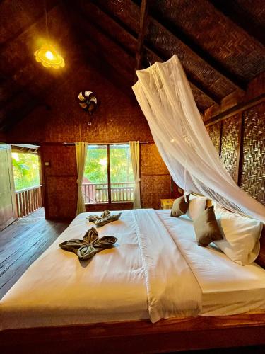 a bedroom with a large white bed with a net at Aulia Bungalows Tetebatu in Tetebatu