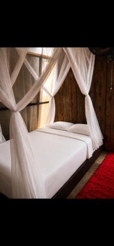 ein Schlafzimmer mit einem Himmelbett mit weißen Laken in der Unterkunft Amazon Oasis in Leticia