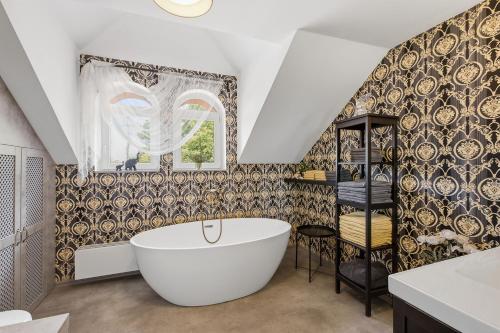 a bathroom with a large tub and a patterned wall at Vila v Lahošti in Teplice