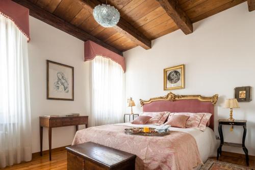 a bedroom with a large bed and a wooden ceiling at Palazzo Benassi Penthouse nel cuore di Asolo in Asolo