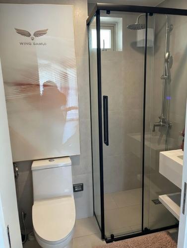 a bathroom with a toilet and a glass shower at กิตติมา อพาร์ทเม้น in Nathon Bay