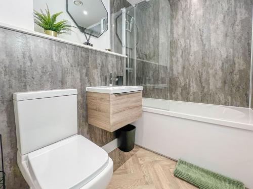 a bathroom with a toilet and a sink and a tub at Copper Suite - 2Bed Elegance - Parking in Liverpool