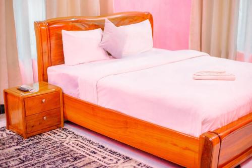 a bed with a wooden headboard and a night stand at MIAMi VILLA HOTEL in Mpanda