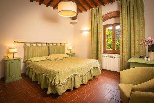 a bedroom with a bed and a chair and a window at Agriturismo Castello Di Querceto in Lucolena in Chianti