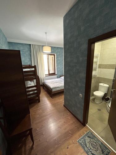 a bathroom with a toilet and a bed in a room at Hill House in Kazbegi