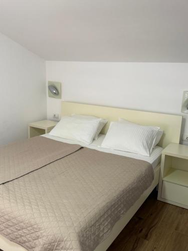 a bedroom with a bed with white sheets and pillows at Apartments Boss in Budva