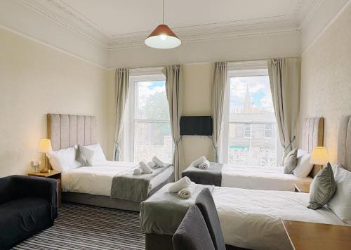 a hotel room with three beds and a couch at Edinburgh full bliss in Edinburgh