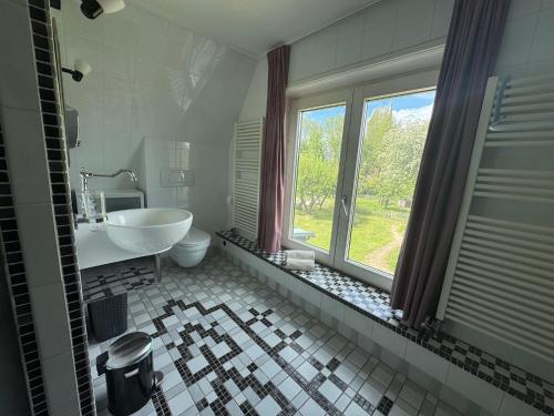 a bathroom with a tub and a sink and a window at B&B Pastorie Jelsum in Jelsum