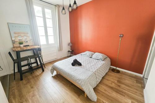 a bedroom with an orange wall with a bed and a desk at "Les Arches 2" City Center Studio in Saintes