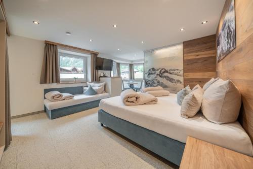 a hotel room with two beds and a couch at Garni Ötztal ROOMS & APARTS in Sölden