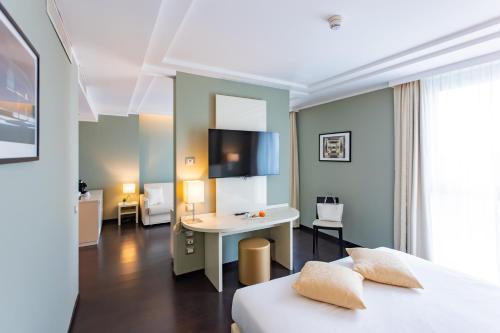 a hotel room with a bed and a desk at AN Hotel Milano Melegnano in Carpiano