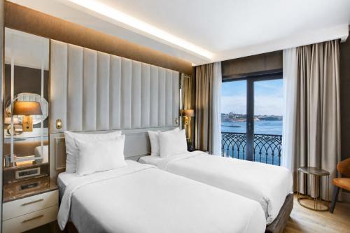 two beds in a hotel room with a balcony at Grand Galata Hotel & Spa in Istanbul