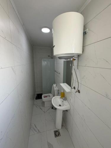 a white bathroom with a sink and a toilet at Apartments Gzim Peja in Ulcinj