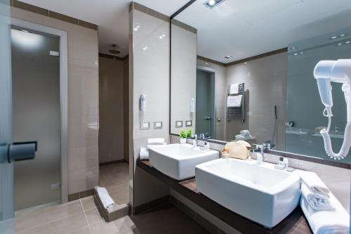 a bathroom with two sinks and a large mirror at AN Hotel Milano Melegnano in Carpiano