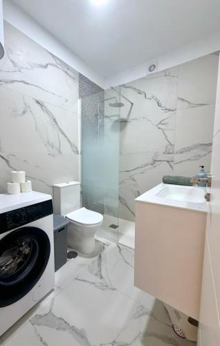 a white bathroom with a toilet and a washing machine at Seguro Spacious apartment with roomy terrace, newly renovated in Puerto de Santiago