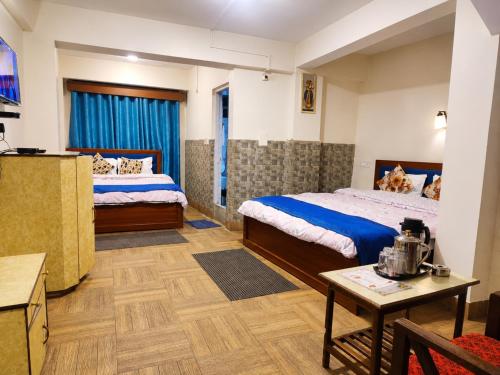 a hotel room with two beds and a table at Hotel Darjeeling palace in Darjeeling
