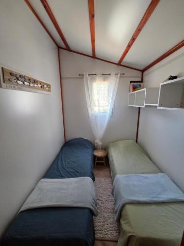 two beds in a small room with a window at Chalet tout confort in Rivières