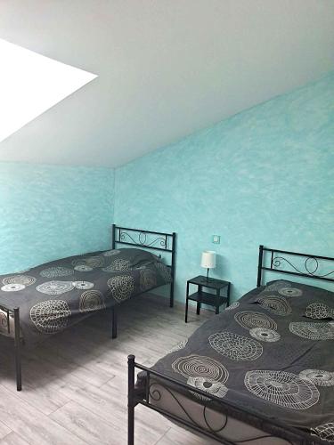 two beds in a room with blue walls at Le Galaveyson in Saint-Clair-sur-Galaure