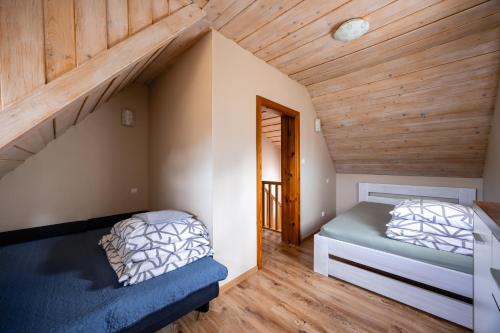 two beds in a room with wooden ceilings at Mazurski domek in Mrągowo