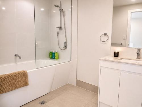 a white bathroom with a shower and a sink at 20 Pimpama Home in Pimpama