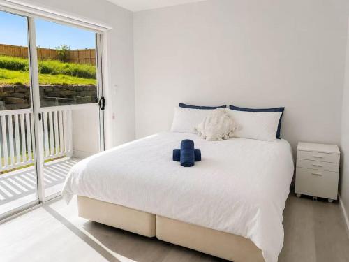 a bedroom with a white bed with a blue pillow on it at 20 Pimpama Home in Pimpama