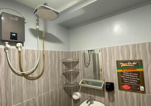 a shower in a bathroom with a sink and a mirror at Amplayo Apartelle 2-BR Unit in Cagayan de Oro