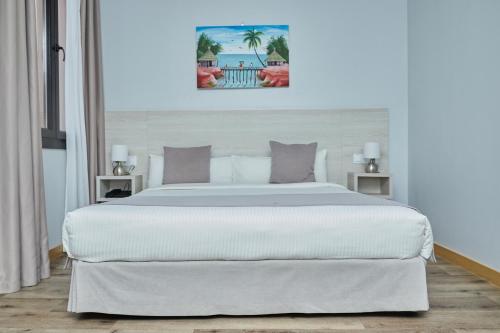 a large white bed in a bedroom with a painting on the wall at Le Grand Hôtel de Thiès in Thiès