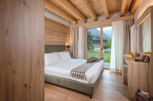 a bedroom with a bed and a large window at LVG Hotel Collection - Cascata d'Otro Mountain Lodge in Alagna Valsesia