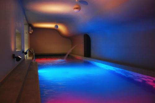 uma piscina com luzes azuis e vermelhas num quarto em Hotel Fado Spa & Restaurant em Świdnica