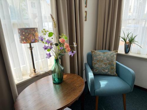 a vase of flowers on a table next to a chair at Hanzestadslogement "De Leeuw", logies in het centrum van Deventer in Deventer