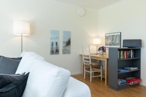 a living room with a table and a desk with a chair at Hohrott 17 Villa Bellevue I in Heikendorf