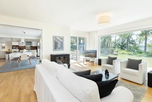 a living room with white furniture and a dining room at Hohrott 17 Villa Bellevue I in Heikendorf