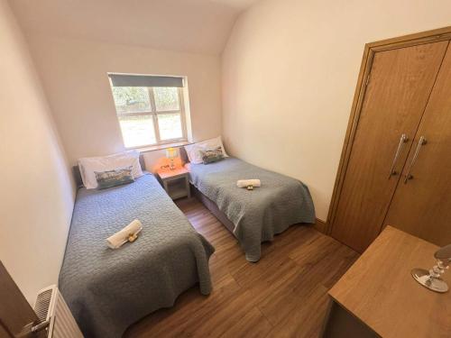 a room with two beds and a window at Maple Lodge Cottage in Blagdon
