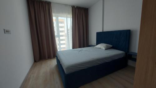 a bedroom with a bed with a blue headboard and a window at 85th Pool View 2 Rooms Apartament in Popeşti-Leordeni