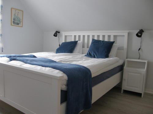 a white bed with blue pillows in a bedroom at Monicas Rumsuthyrning in Borgholm